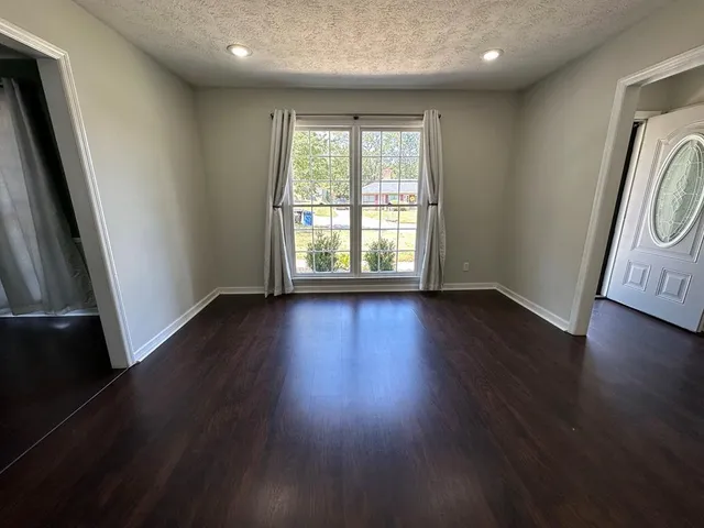 an empty room with wooden floor and window
