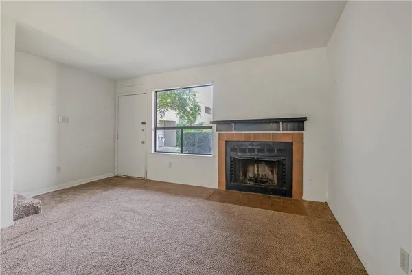 a view of an empty room with a window and fireplace