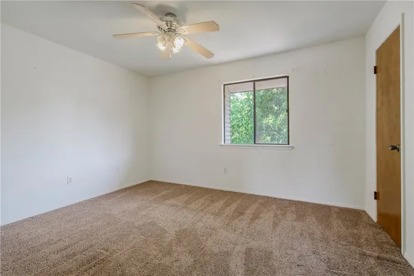 an empty room with a window and a fan