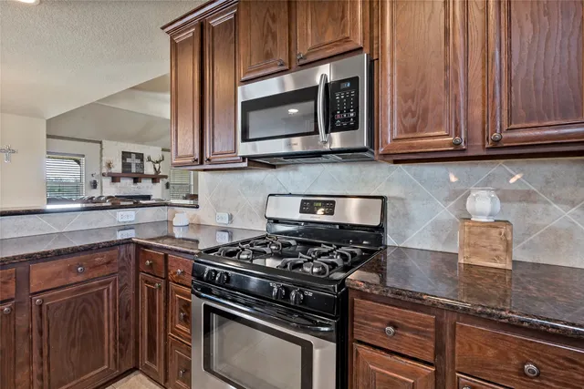 a kitchen with kitchen island granite countertop wooden cabinets stainless steel appliances and a counter space