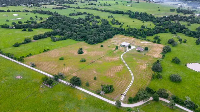 an aerial view of residential houses with outdoor space and trees
