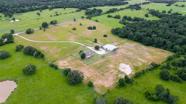 an aerial view of a houses with outdoor space and trees all around