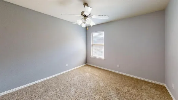 an empty room with windows and chandelier fan
