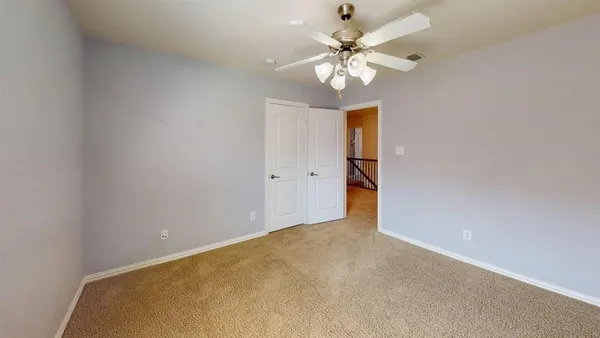 a view of an empty room with a chandelier fan