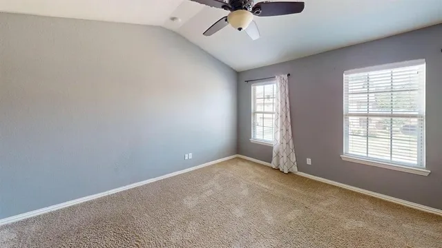 an empty room with a window and ceiling fan