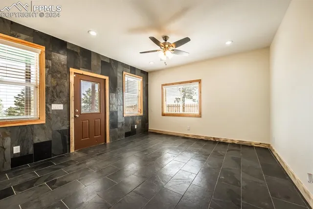 an empty room with windows and fan