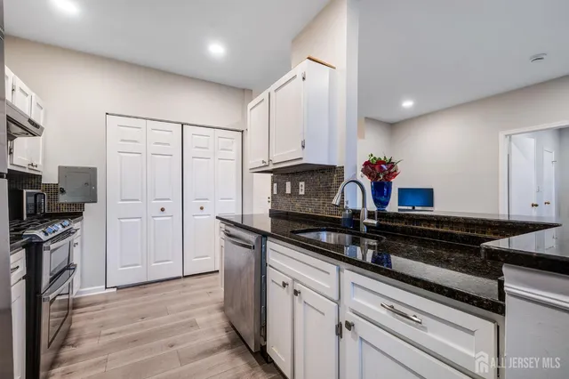 a kitchen with granite countertop a sink cabinets and stainless steel appliances