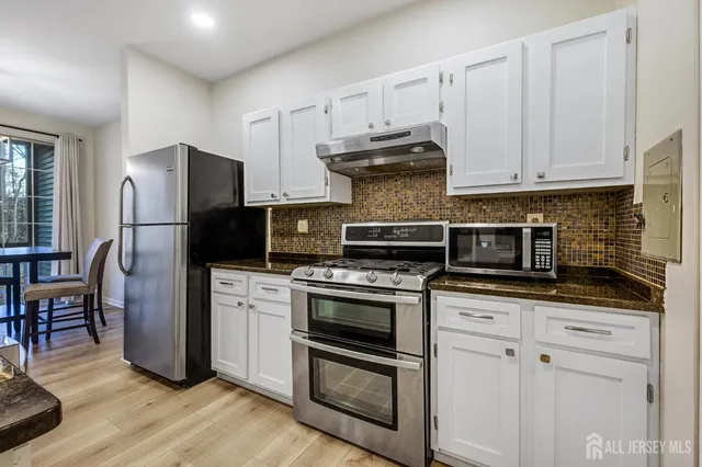 a kitchen with stainless steel appliances granite countertop a stove a refrigerator and a microwave