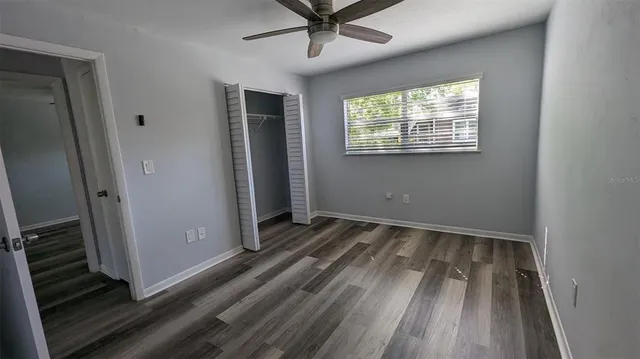 a view of an empty room with wooden floor and a window