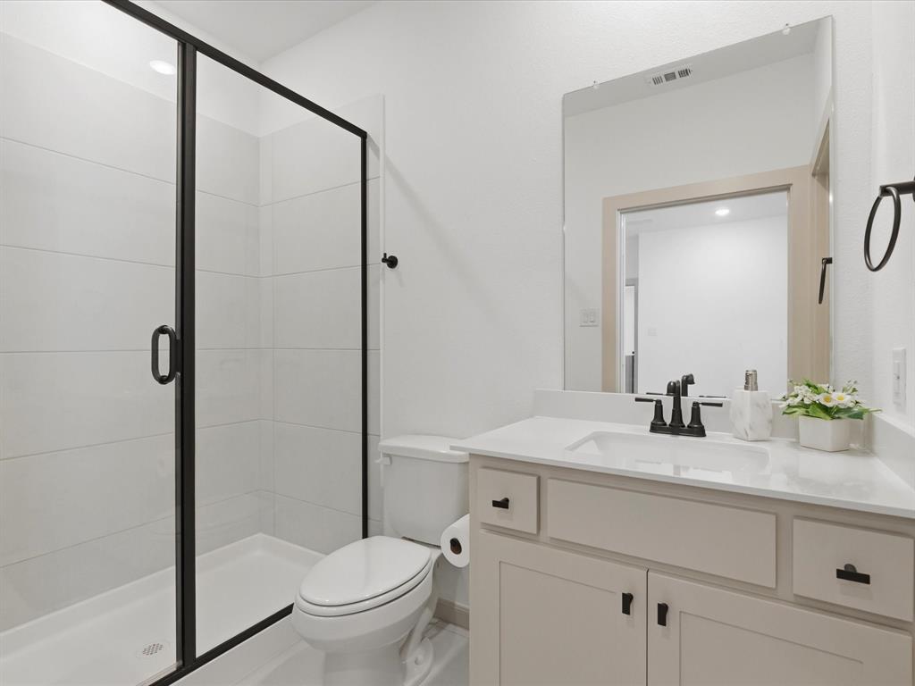 9533 Keep Street Frisco, TX 75035 - Photo 31 of 40 Bathroom featuring a glass-enclosed shower with black trim, a white vanity with an integrated sink, a large wall-mounted mirror, and black fixtures
