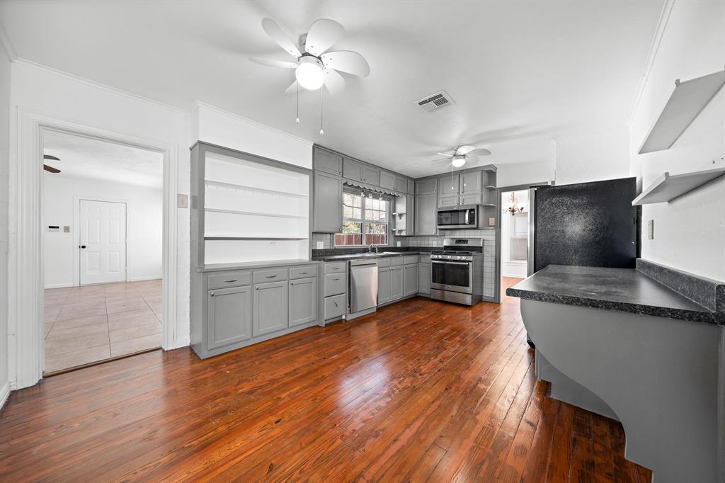 3119 Trice Avenue Waco, TX 76707 - Photo 26 of 40 a kitchen with stainless steel appliances kitchen island granite countertop a refrigerator a stove and a sink with wooden floor