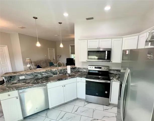 a kitchen with stainless steel appliances granite countertop a stove a sink and a microwave