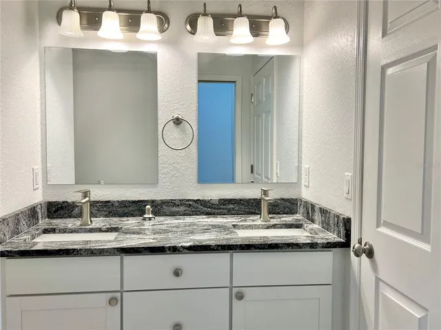 a bathroom with a granite countertop sink and a mirror