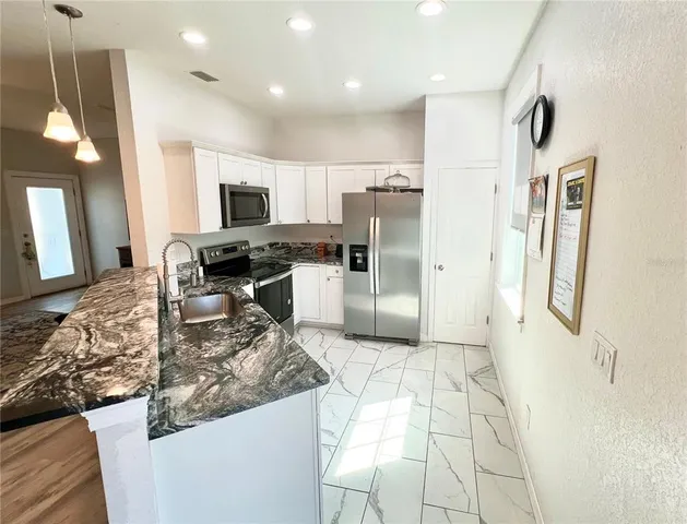 a kitchen with stainless steel appliances granite countertop a refrigerator and a stove top oven
