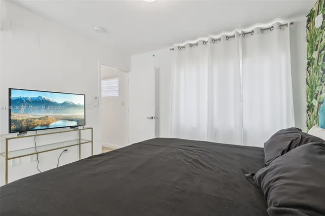 a bedroom with a bed and a flat tv screen on wall