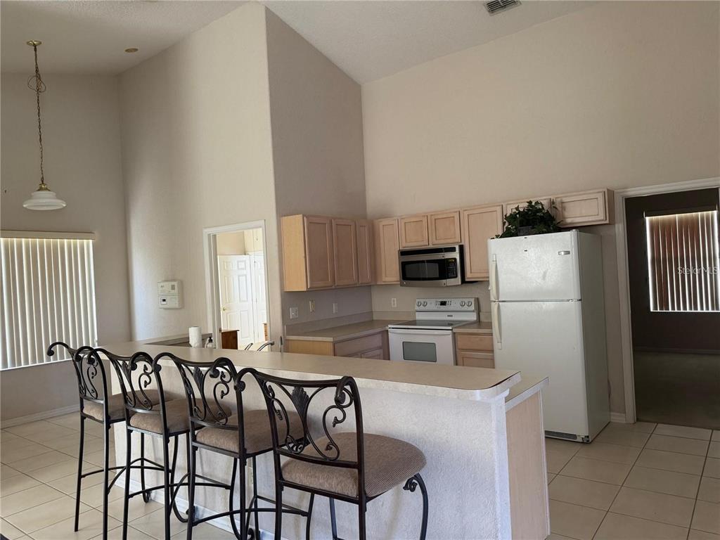 525 Corvina Drive Davenport, FL 33897 - Photo 4 of 15 a kitchen with stainless steel appliances a stove a sink a microwave a refrigerator and white cabinets