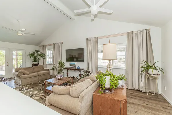 a living room with furniture hard wood floor and a floor to ceiling window