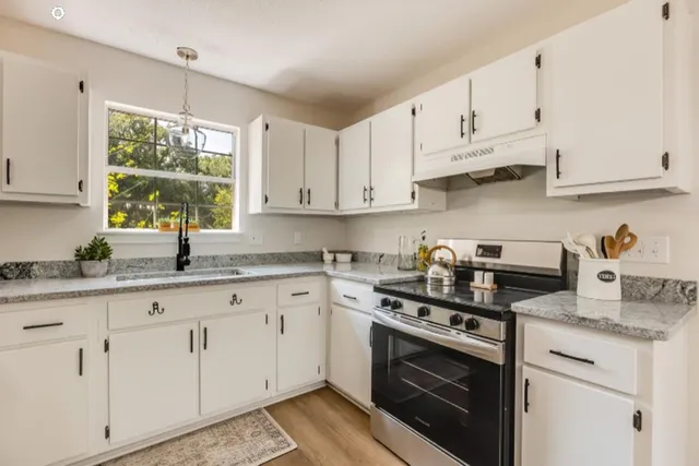 a view of a kitchen with a sink dishwasher stove and refrigerator with wooden floor