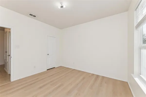 an empty room with wooden floor ceiling fan and windows