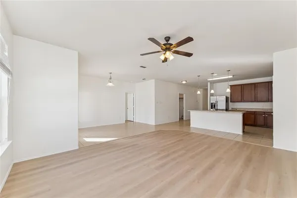a view of an empty room with kitchen and kitchen view