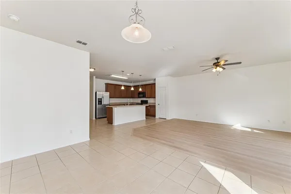 a view of kitchen and empty room with wooden floor