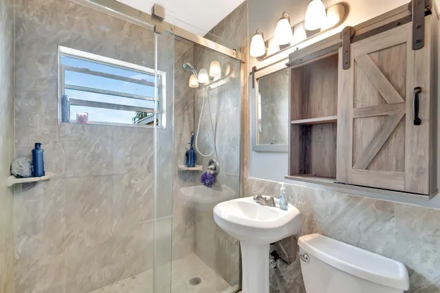 a bathroom with a sink a toilet a mirror and shower