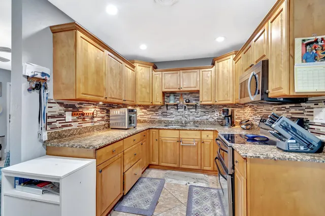 a kitchen with stainless steel appliances granite countertop a sink a stove and a refrigerator