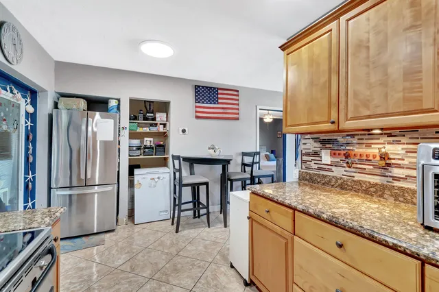 a kitchen with granite countertop a refrigerator and a stove top oven