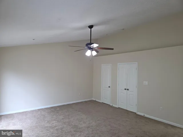 a view of an empty room with a chandelier fan