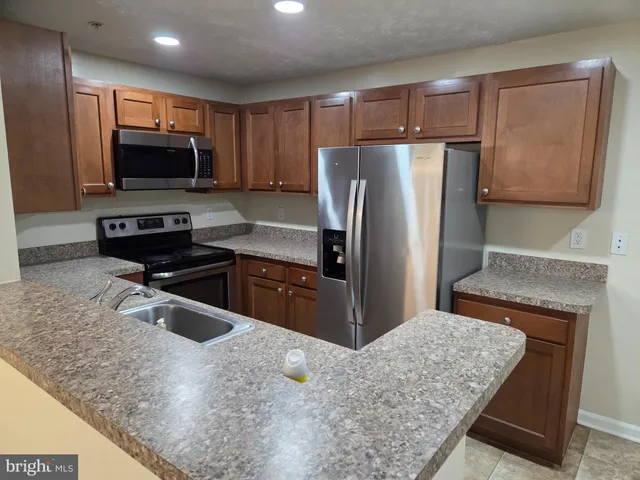 a kitchen with stainless steel appliances granite countertop a refrigerator and a stove top oven