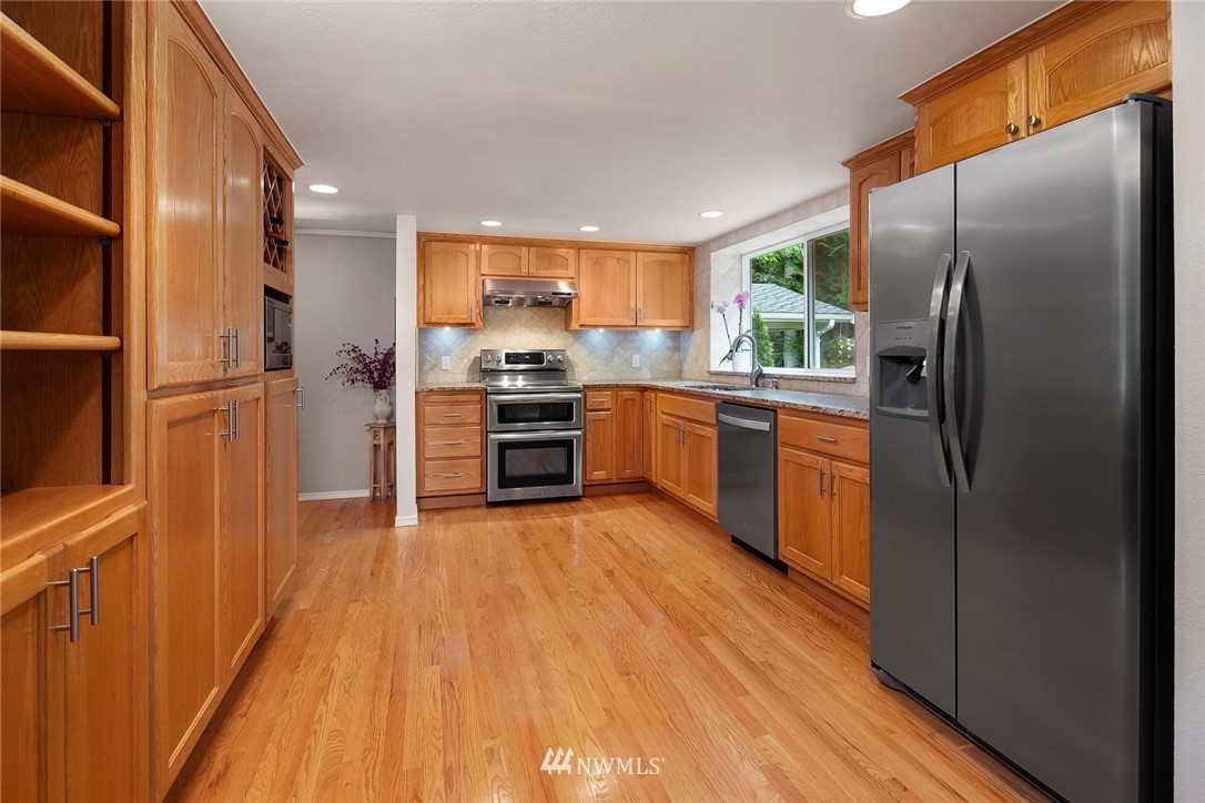 22303 49th Avenue Southeast Bothell, WA 98021 - Photo 9 of 25 a kitchen with stainless steel appliances granite countertop a refrigerator a stove and a wooden floors