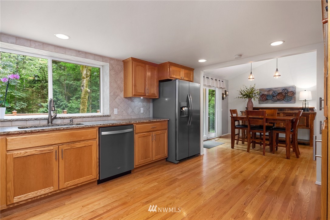 22303 49th Avenue Southeast Bothell, WA 98021 - Photo 10 of 25 a kitchen with stainless steel appliances granite countertop a refrigerator a sink dishwasher a stove and a dining table with wooden floor
