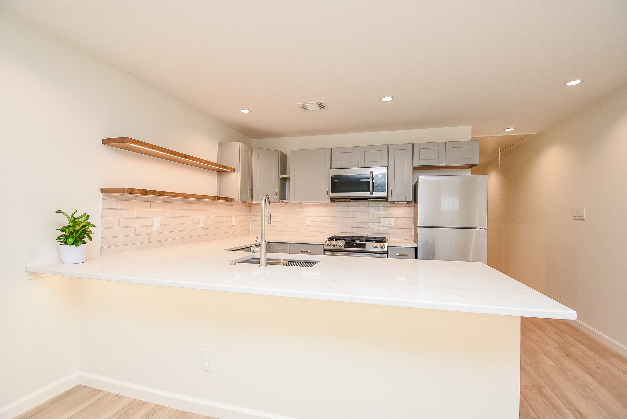 2509 Terry Street, Unit A Houston, TX 77009 - Photo 13 of 22 a kitchen with stainless steel appliances a refrigerator a sink a stove a microwave a sink and white cabinets with wooden floor