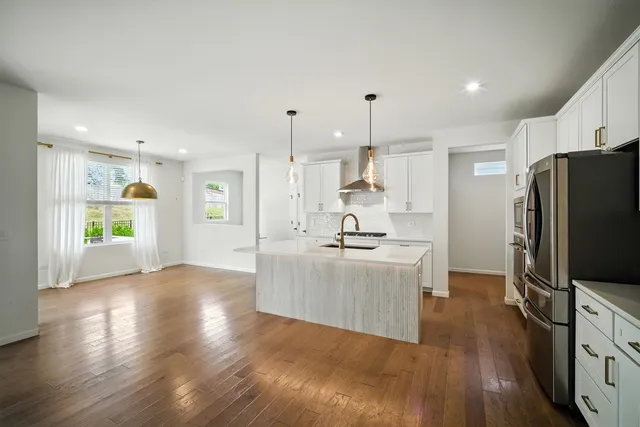 a kitchen with stainless steel appliances kitchen island wooden floors wooden cabinets and refrigerator