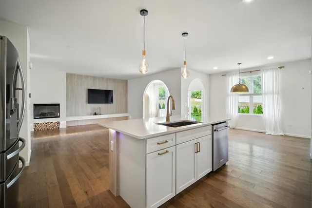 a kitchen with stainless steel appliances granite countertop a sink a stove and a wooden floors