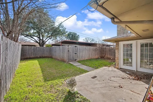 a view of a backyard with large trees and wooden fence