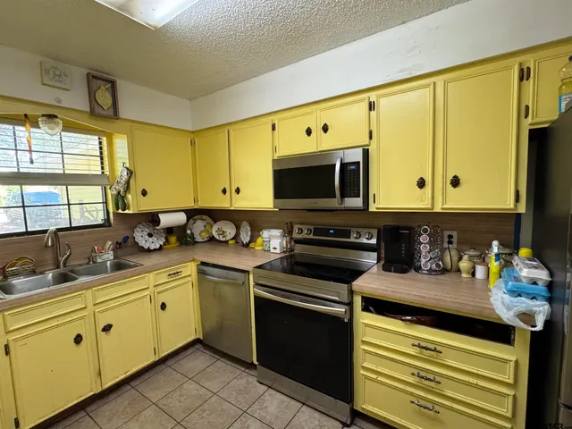 a kitchen with stainless steel appliances a stove a sink cabinets and a microwave
