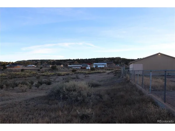 a view of a dry yard with wooden fence
