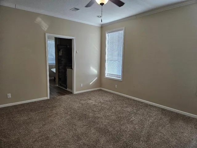an empty room with windows and chandelier fan