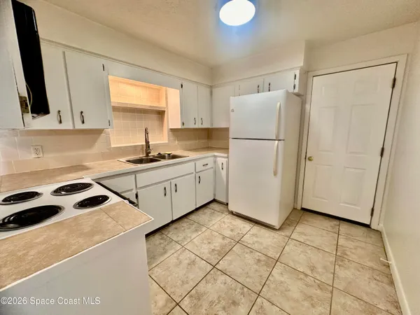 a kitchen with a sink a refrigerator a window and cabinets
