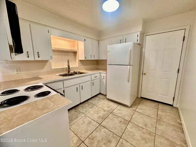 a kitchen with a sink a refrigerator a window and cabinets