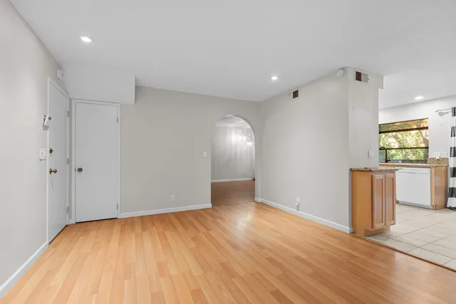 a view of an empty room with window and wooden floor