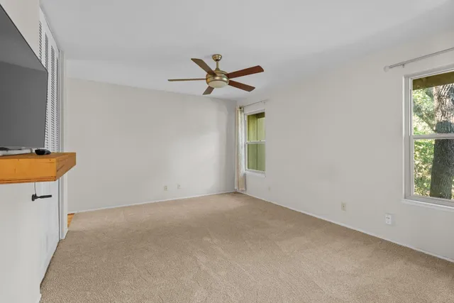 an empty room with windows and a ceiling fan