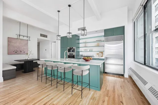 a kitchen with stainless steel appliances a dining table chairs and wooden floor