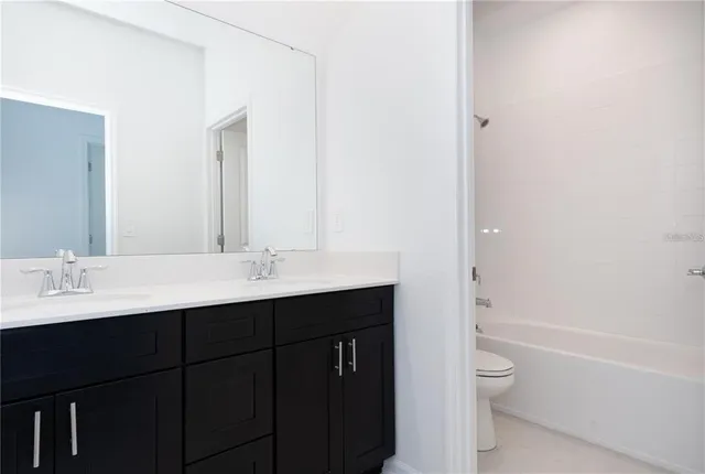 a bathroom with a bathtub sink vanity mirror and toilet