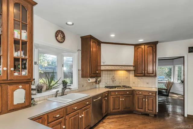 a kitchen with kitchen island granite countertop wooden cabinets a sink a window and stainless steel appliances