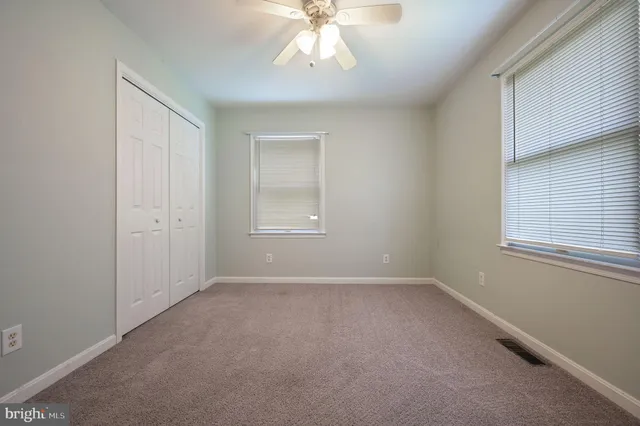 an empty room with chandelier fan and windows