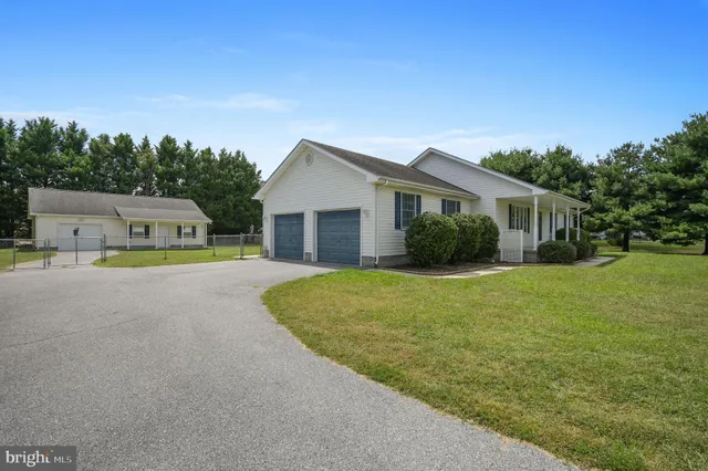 a yellow house with a big yard plants and large trees