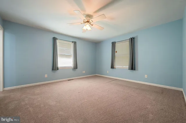 an empty room with windows and chandelier fan