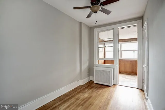 a view of an empty room with a window and wooden floor